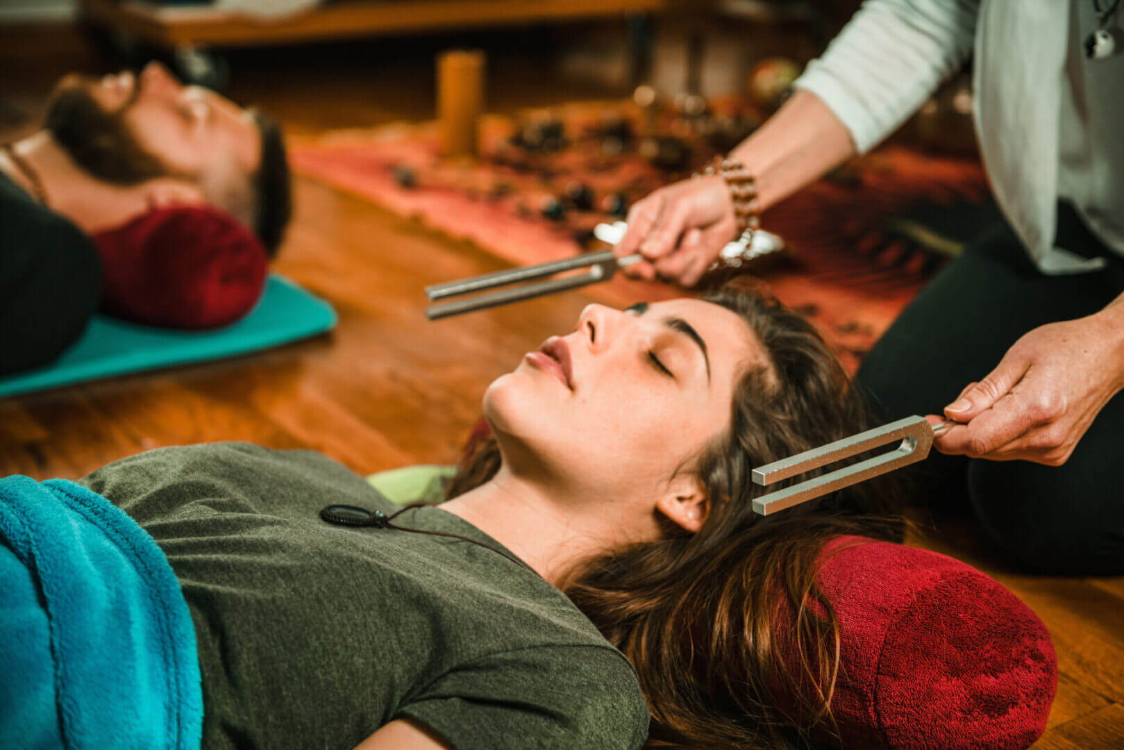 A person holding a tuning fork to a woman's face.