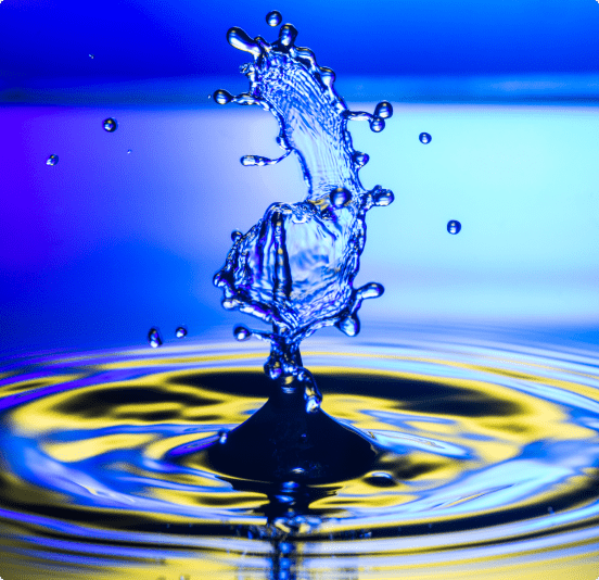 Water splash creating droplets against a blue background.